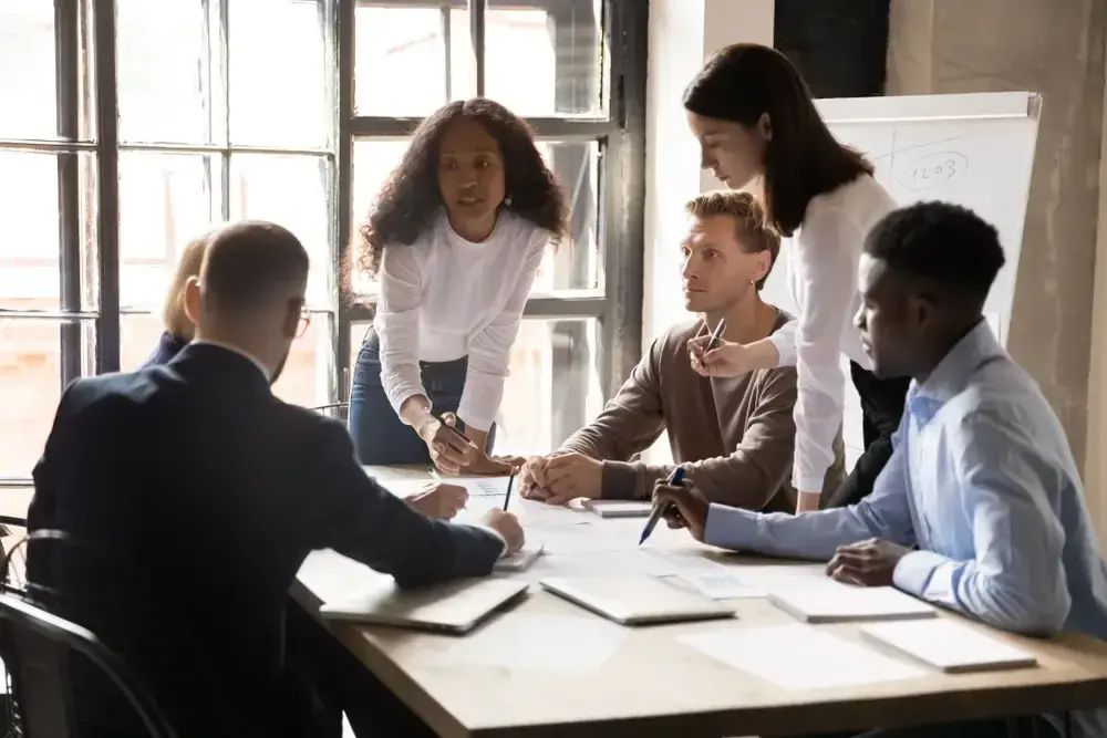A diverse group of five people are gathered around a table in a T-Group