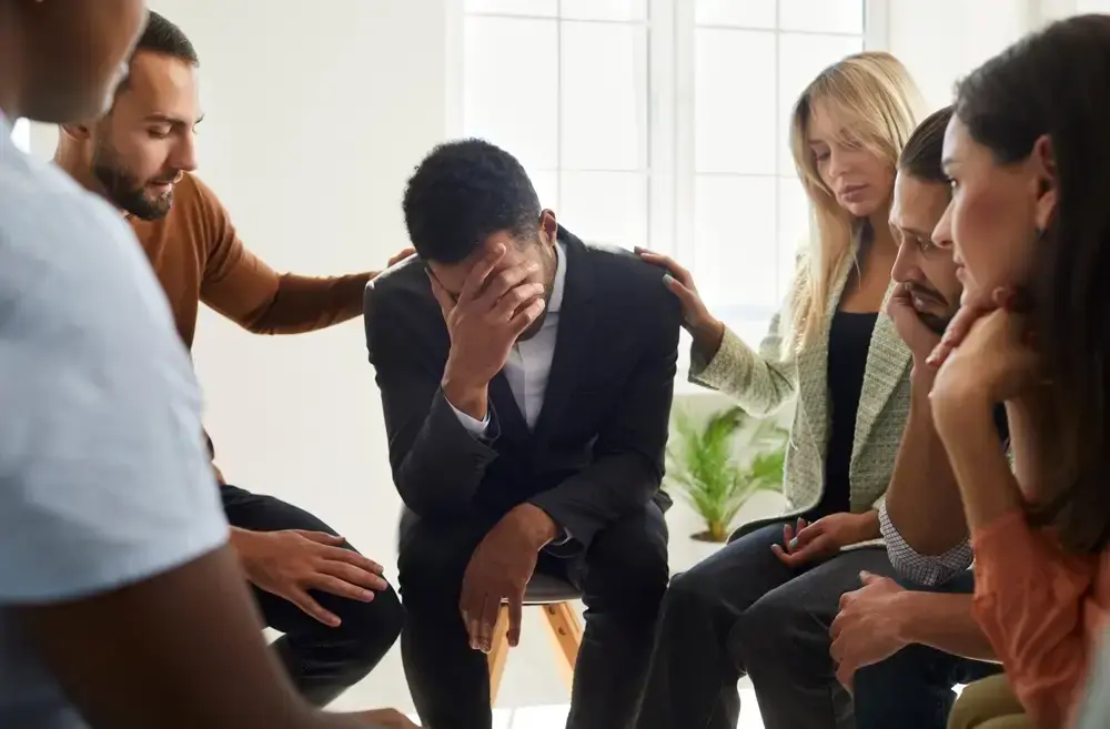 A group of six people sit in a circle during group therapy