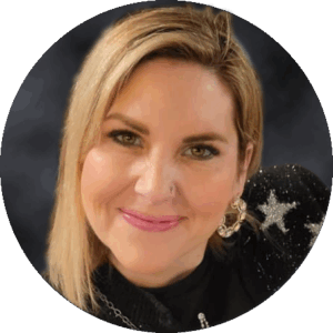 Trudy therapist with blonde hair, smiles at the camera in a black top adorned with star patterns and a large earring, set against a dark background.