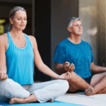 Two adults sit cross-legged on yoga mats, meditating with eyes closed and hands resting on their knees—a serene moment of relationship growth during a personalized couples retreat in a calm indoor space.