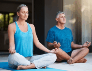 Two adults sit cross-legged on yoga mats, meditating with eyes closed and hands resting on their knees—a serene moment of relationship growth during a personalized couples retreat in a calm indoor space.