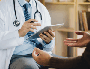 A psychiatrist in a white coat holding a tablet shares expert tips on mental health while speaking with a patient, whose hands are visible in the foreground.