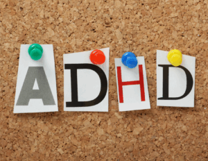 Four letters spelling "ADHD" are pinned to a corkboard with colored push pins, each letter printed on a separate piece of paper—symbolizing support like online ADHD treatment from Bay Area CBT Center.