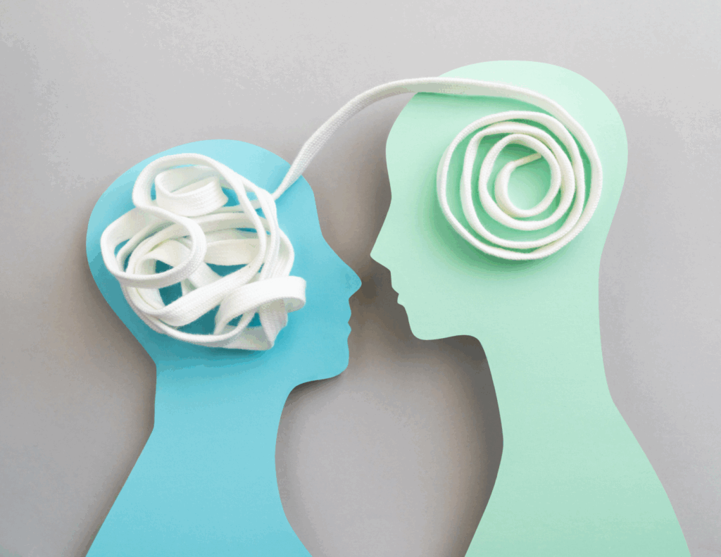 Two silhouette cutouts face each other; a tangled white cord is inside one head and a neatly coiled cord leads to the other, symbolizing how empathy can untangle thoughts and foster clearer communication or knowledge transfer.