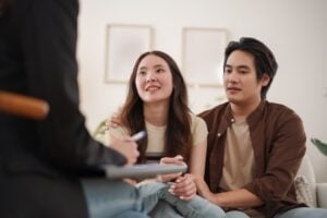 A couple sits close together, listening attentively to a pre marital counselor taking notes during a counseling session—a practical guide for couples in California.